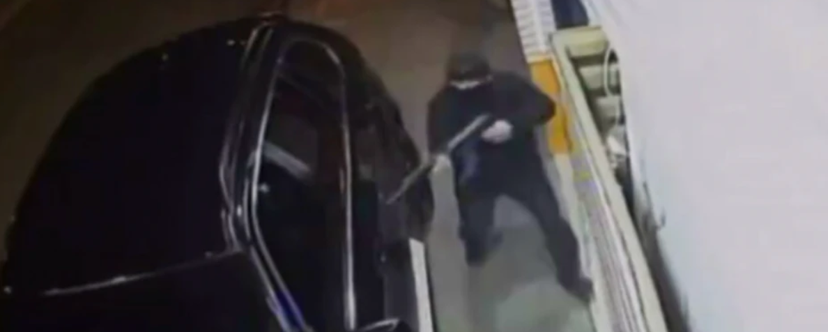 An assassin stands at the driver seat of Vangelis Zambounis with machine gun