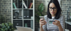 Woman reading credit card while holding phone and sitting in front of laptop